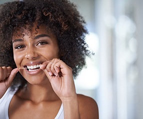 Woman smiling while flossing her teeth